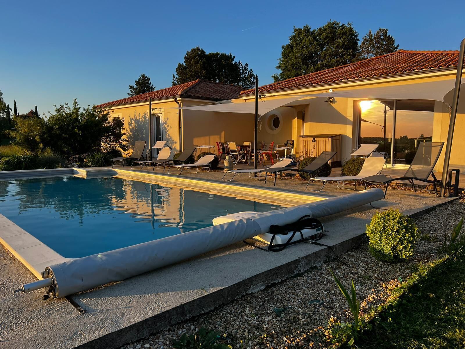 Ein Swimmingpool mit Liegestühlen und einer überdachten Terrassenanlage.