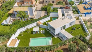 Vista aérea de una zona residencial con casas modernas, piscina y jardines cuidados.