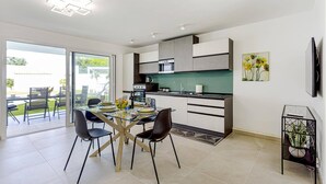 Una cocina moderna con zona de comedor, ventanas amplias y un televisor de pantalla plana.