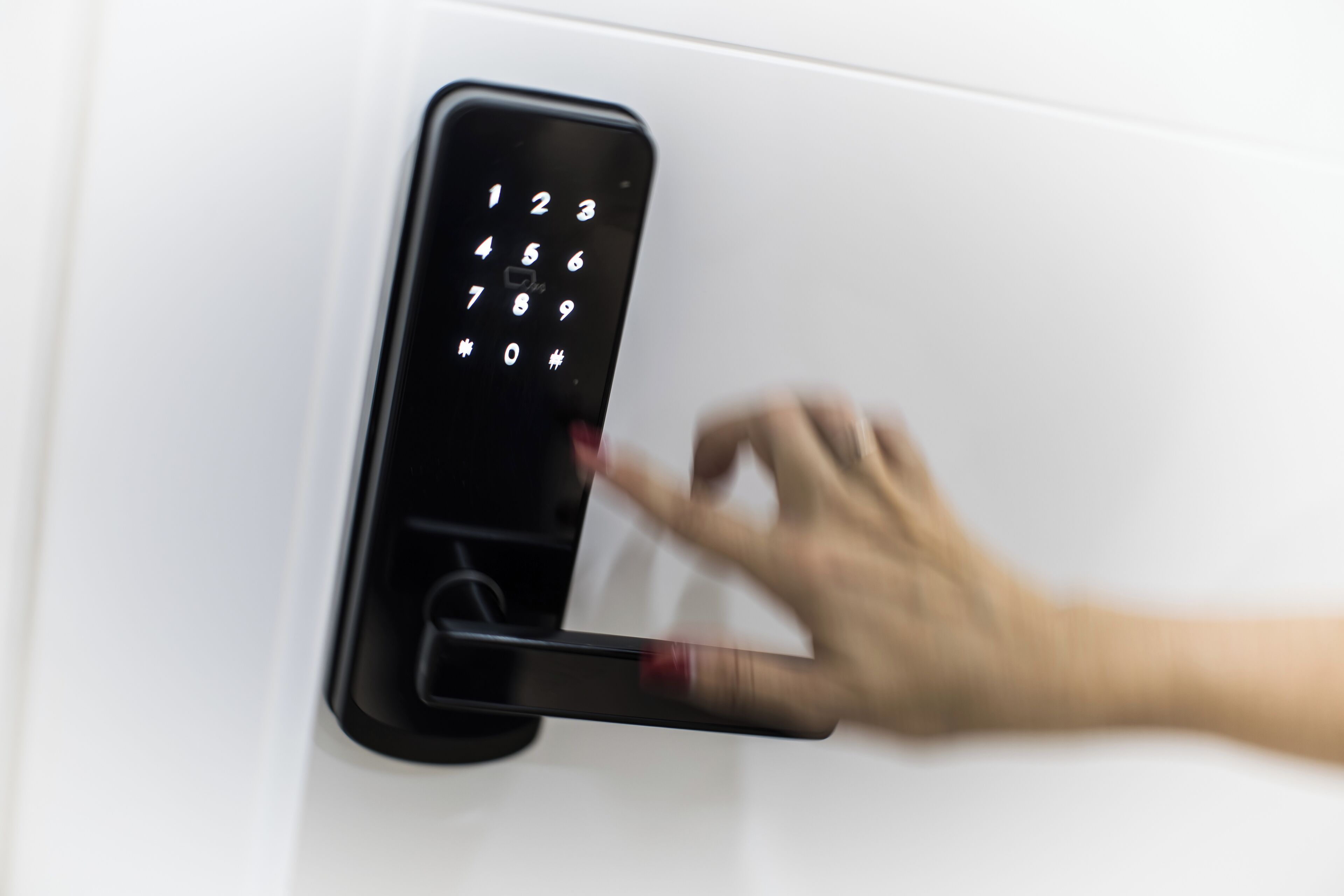 A hand using a numeric keypad on a door lock.