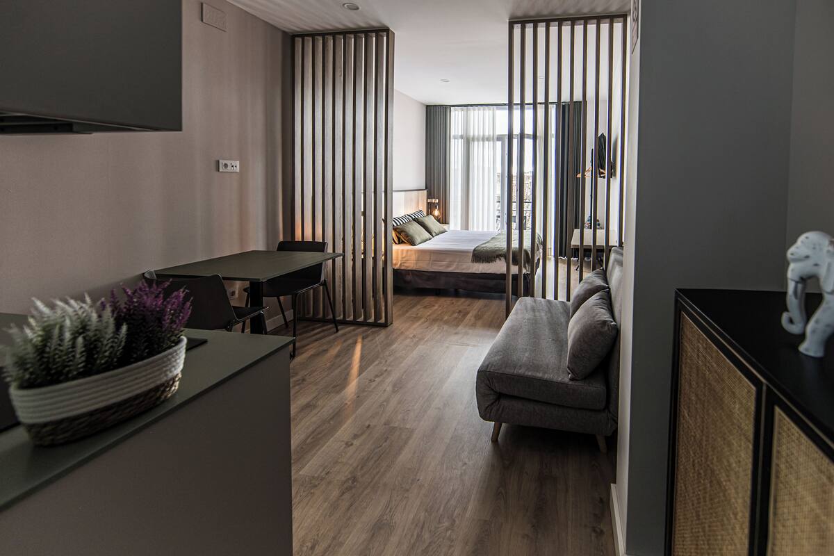 Une chambre d’hôtel moderne avec un plancher en bois, un canapé, une table à manger et un téléviseur.