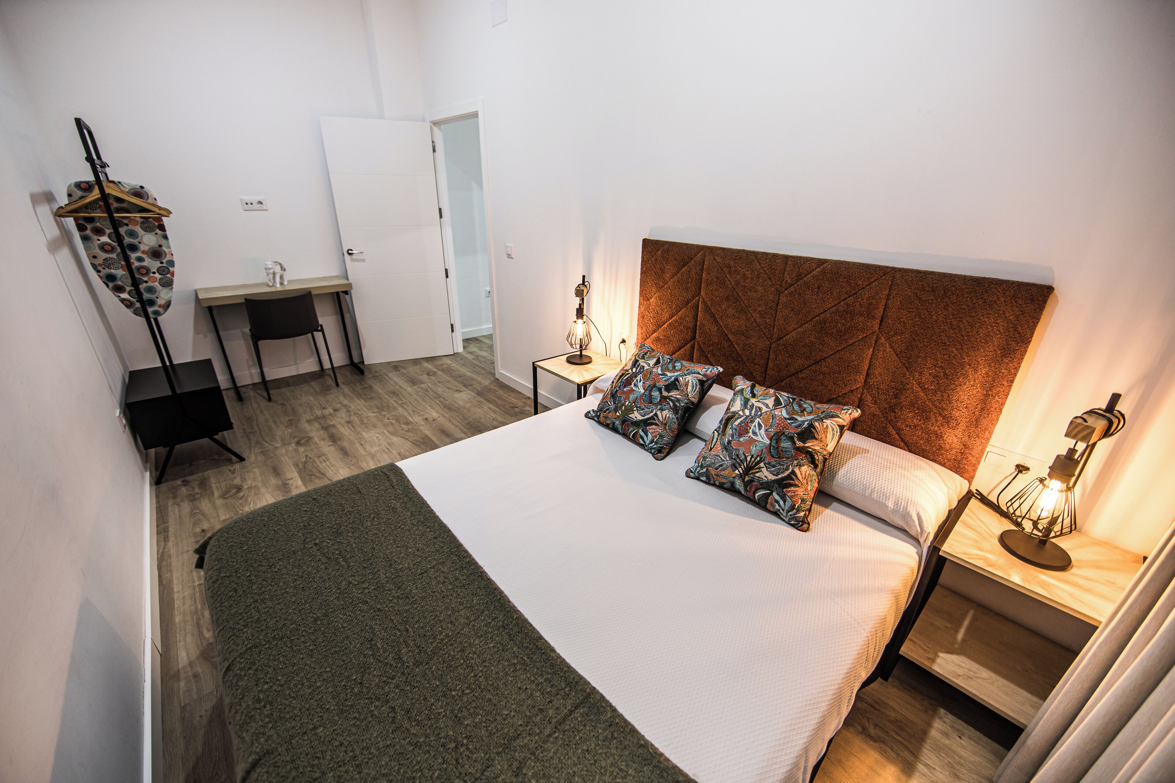 Un dormitorio ordenado con una cama grande, un escritorio y una silla.