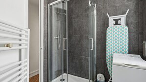 A modern bathroom with a glass-enclosed shower, a white radiator, and a patterned ironing board. - ID 400- MEUNIERS near Bercy lively Area (Paris)