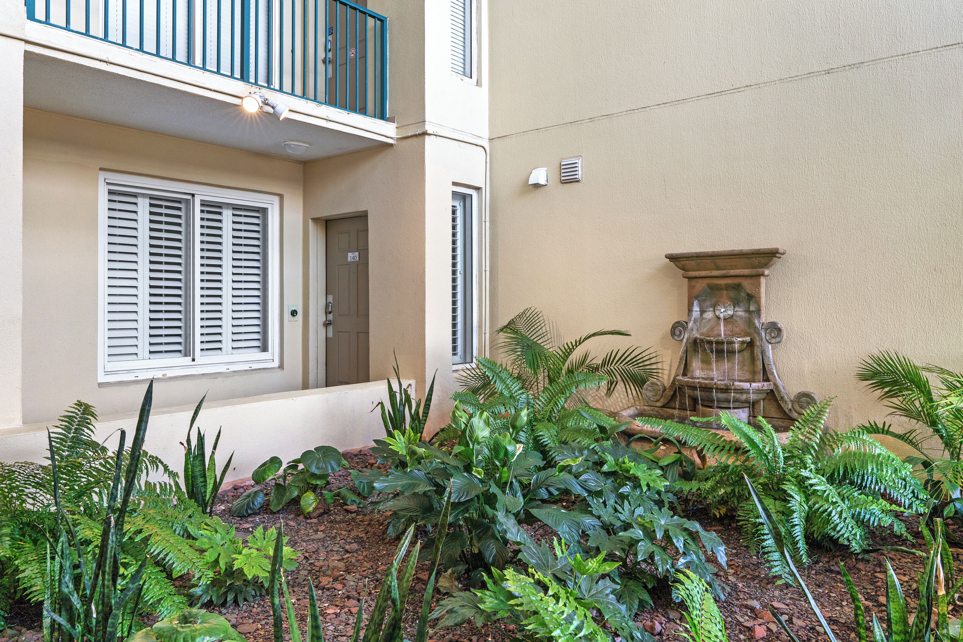 A building with a balcony, a door, and a water feature.