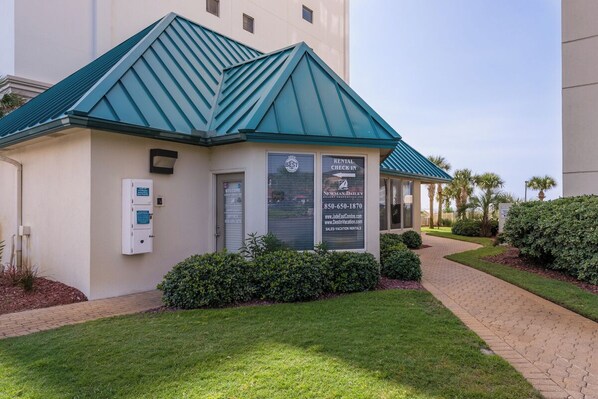 A building with a green roof, a rental check-in sign, and a contact number. - Pool, Beach, Neary Water Park & Destin Harbor (Destin)