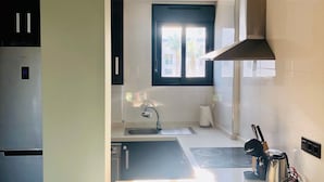 A modern kitchen with a stainless steel refrigerator, a built-in oven, a sink with a faucet, and a window providing natural light. - Penthouse Oasis beach II La zenia (Orihuela Costa)