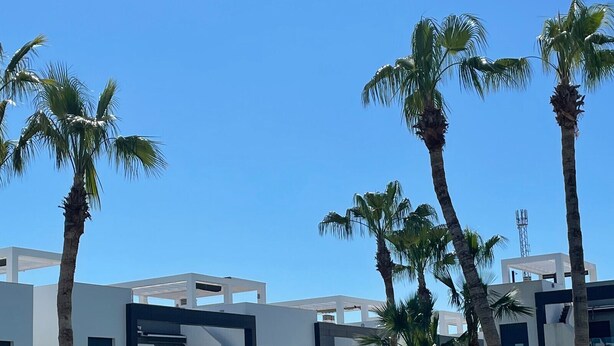 A modern pool area with clear blue water, surrounded by palm trees and contemporary buildings. - Penthouse Oasis beach II La zenia (Orihuela Costa)