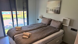 A double bed with a view of a pool and garden through a sliding door. - Penthouse Oasis beach II La zenia (Orihuela Costa)