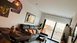 A modern living room with a sofa, dining table, and a large window.