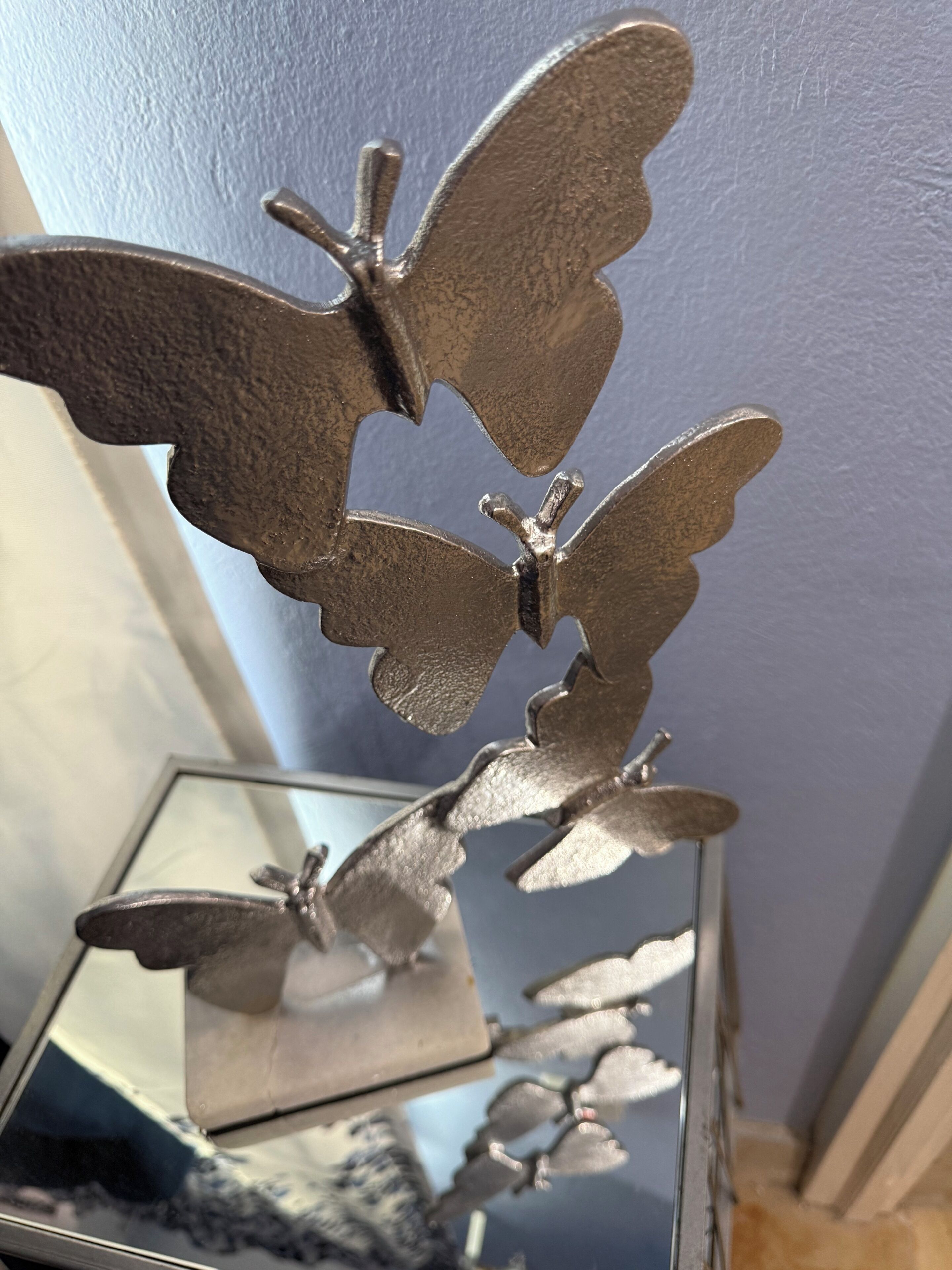 A metallic butterfly sculpture on a reflective surface.
