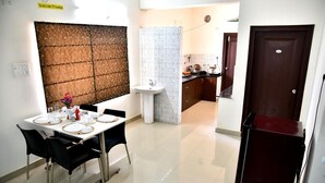 A dining area with a table set for four, a sink, and a kitchen in the background.