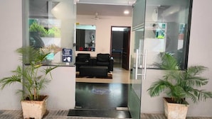 A reception area with a glass door, two potted plants, a seating area with chairs, and a sign indicating temperature control.