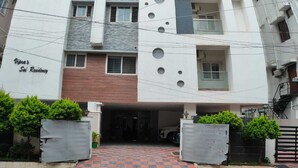 A multi-story residential building with a modern design, featuring a central staircase, balconies, and a gated entrance.