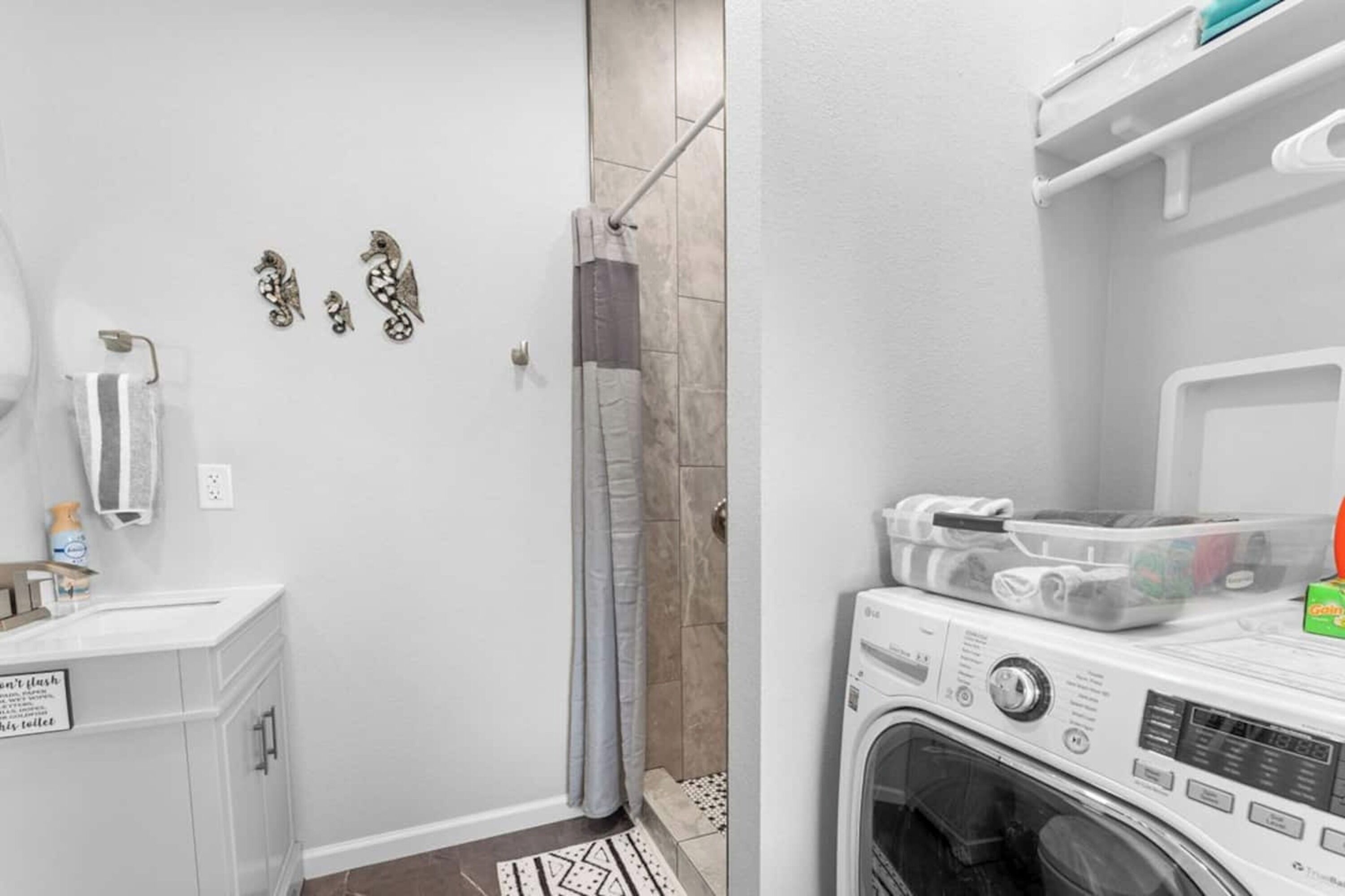 A bathroom with a shower, a toilet, a sink, and a washing machine.