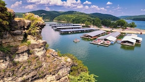 A lakeside marina with docked boats and a series of covered structures, likely for boat storage or maintenance, surrounded by natural scenery and hills. - Romantic Lake Haven - Couples' Cabin (Omaha)