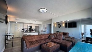 A modern living room with a sectional sofa, a coffee table, and a dining area with a glass table.