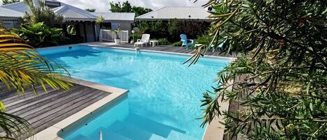 Relax by the serene pool surrounded by lush greenery and a patio.