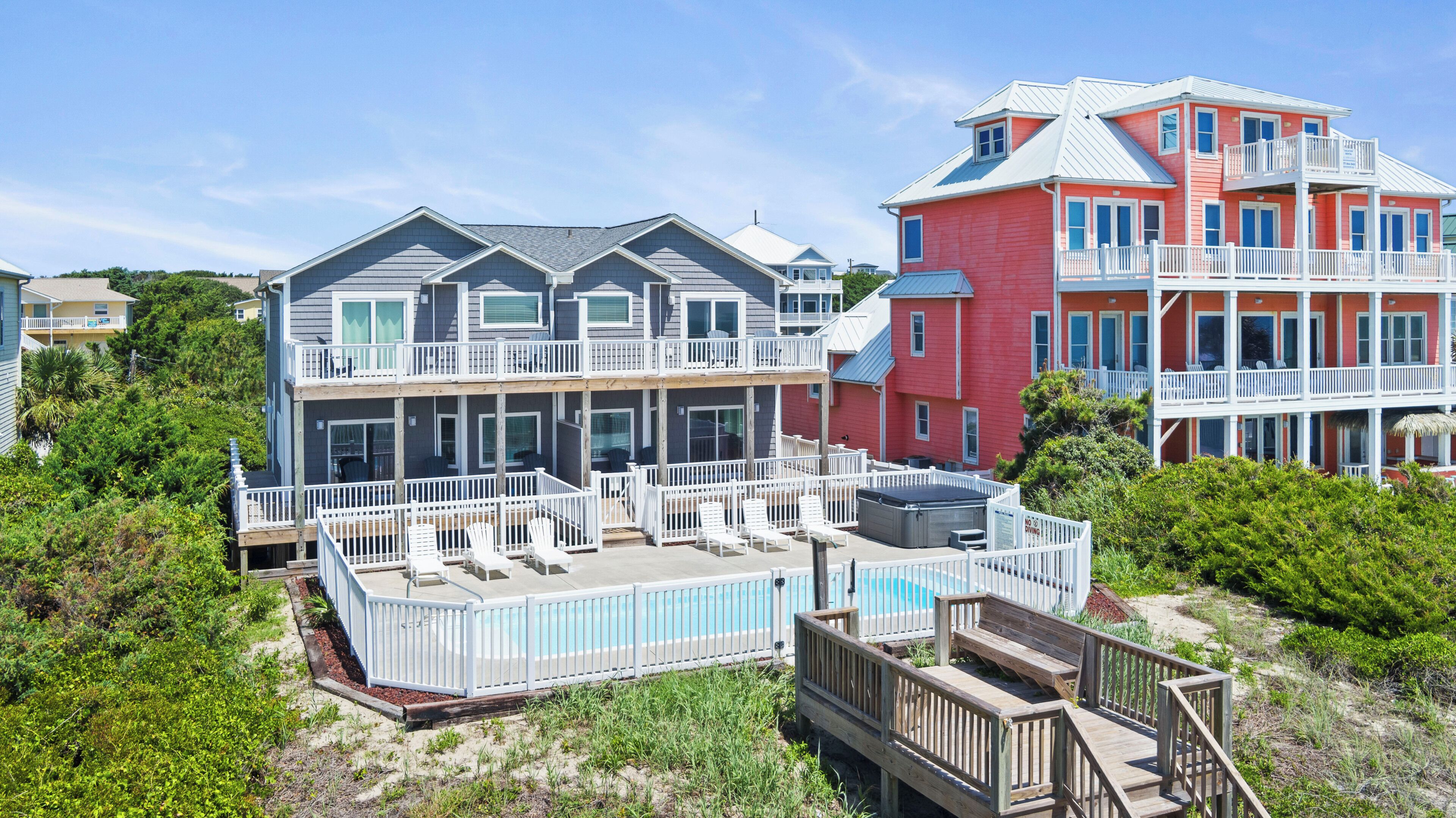 A multi-story beachfront property with a pool, multiple balconies, and a deck area.