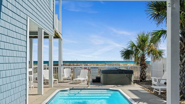 A swimming pool with a view of the beach, white outdoor furniture, and a covered hot tub. - Luxury Oceanfront Home: Private Pool, Elevator Access, Game Room & More! (Emerald Isle)