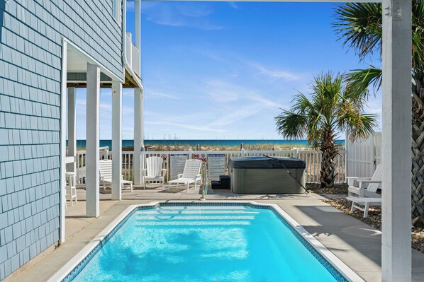 A swimming pool with a view of the beach, white outdoor furniture, and a covered hot tub. - Luxury Oceanfront Home: Private Pool, Elevator Access, Game Room & More! (Emerald Isle)