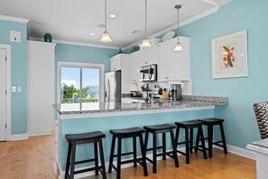 Una cocina moderna con una isla grande, electrodomésticos de acero inoxidable y taburetes negros.
