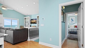A spacious living area with a view of the ocean, a balcony, and a dining area with a view. - Luxury Oceanfront Home: Private Pool, Elevator Access, Game Room & More! (Emerald Isle)