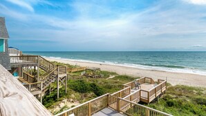 A beach house with wooden decks and a view of the ocean. - Oceanfront 8 Bedroom/6.5 Bath Home: Elevator, Gourmet Kitchen, Pool, Hot Tub, St (Emerald Isle)