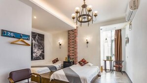 Une chambre à coucher comprenant un lit, une chaise, un luminaire suspendu, un mur en briques et une petite table avec une chaise.