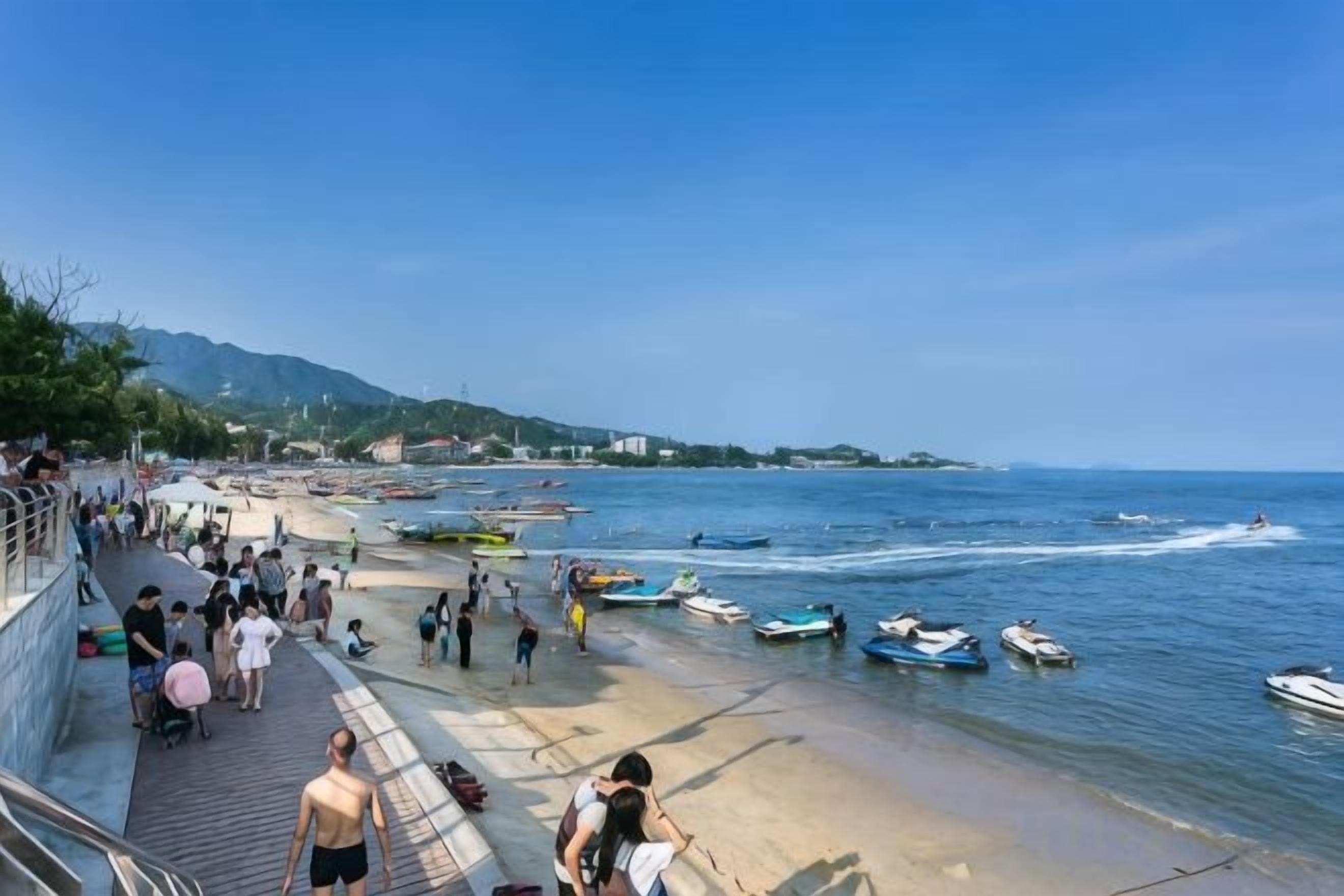 Une scène de plage côtière avec des personnes, des bateaux et un jet ski.