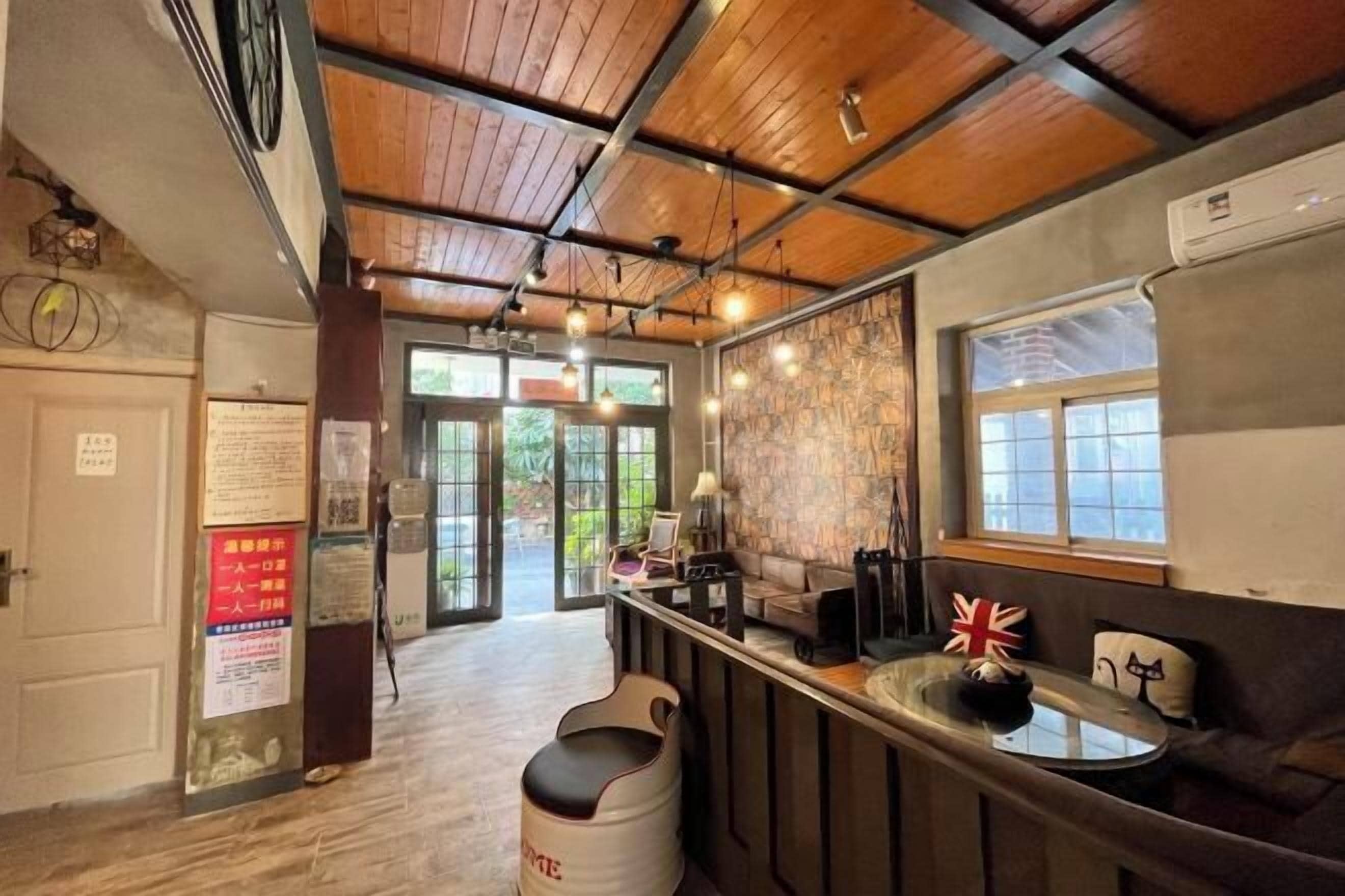A bar area with a wooden ceiling, a counter with stools, and a view through the glass doors.