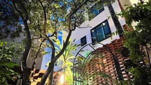Une cour avec un mur en briques, une pergola en bois et un bâtiment blanc doté de fenêtres.