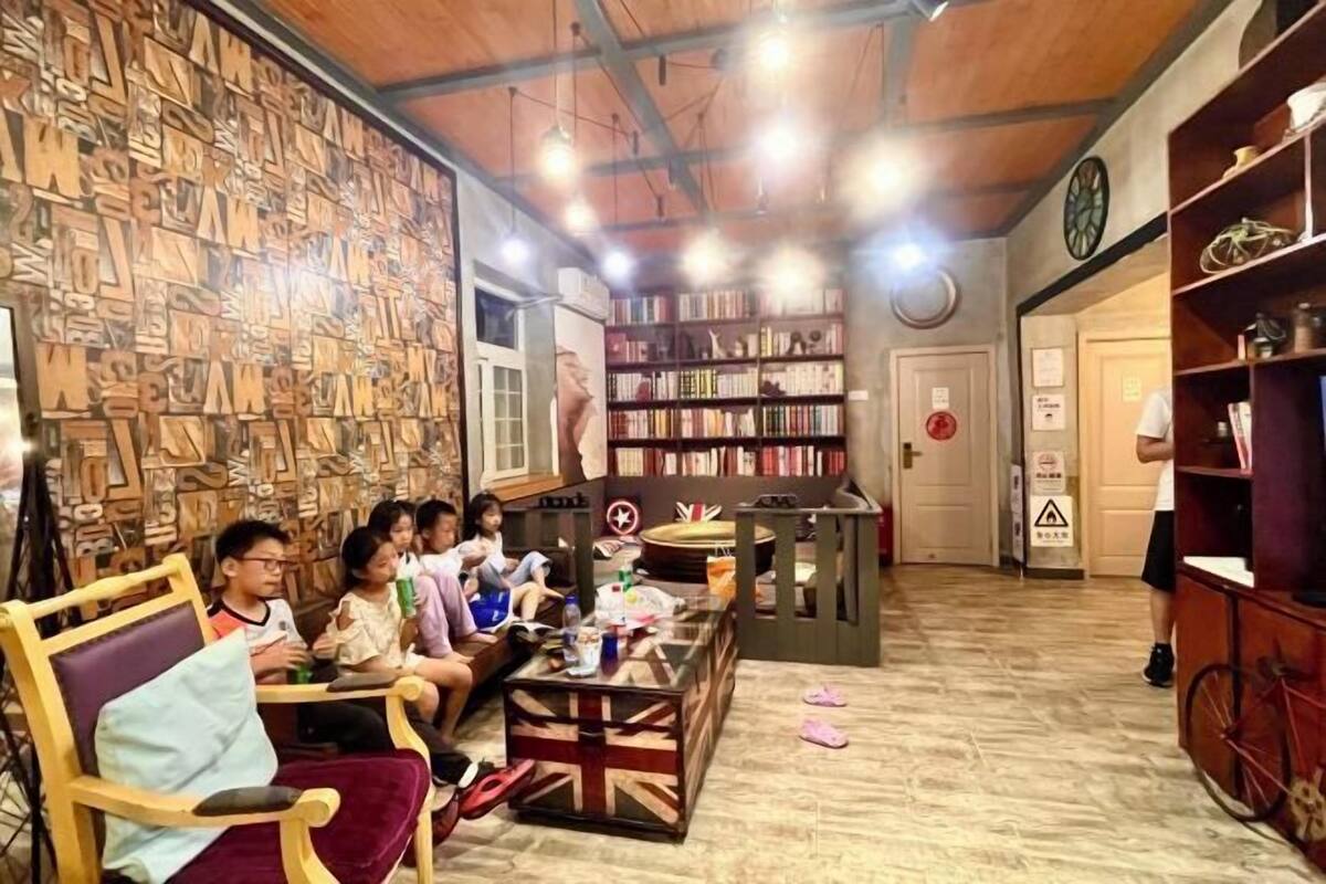 Una habitación acogedora con una pared de madera, una estantería, una mesa con bebidas y una bicicleta.
