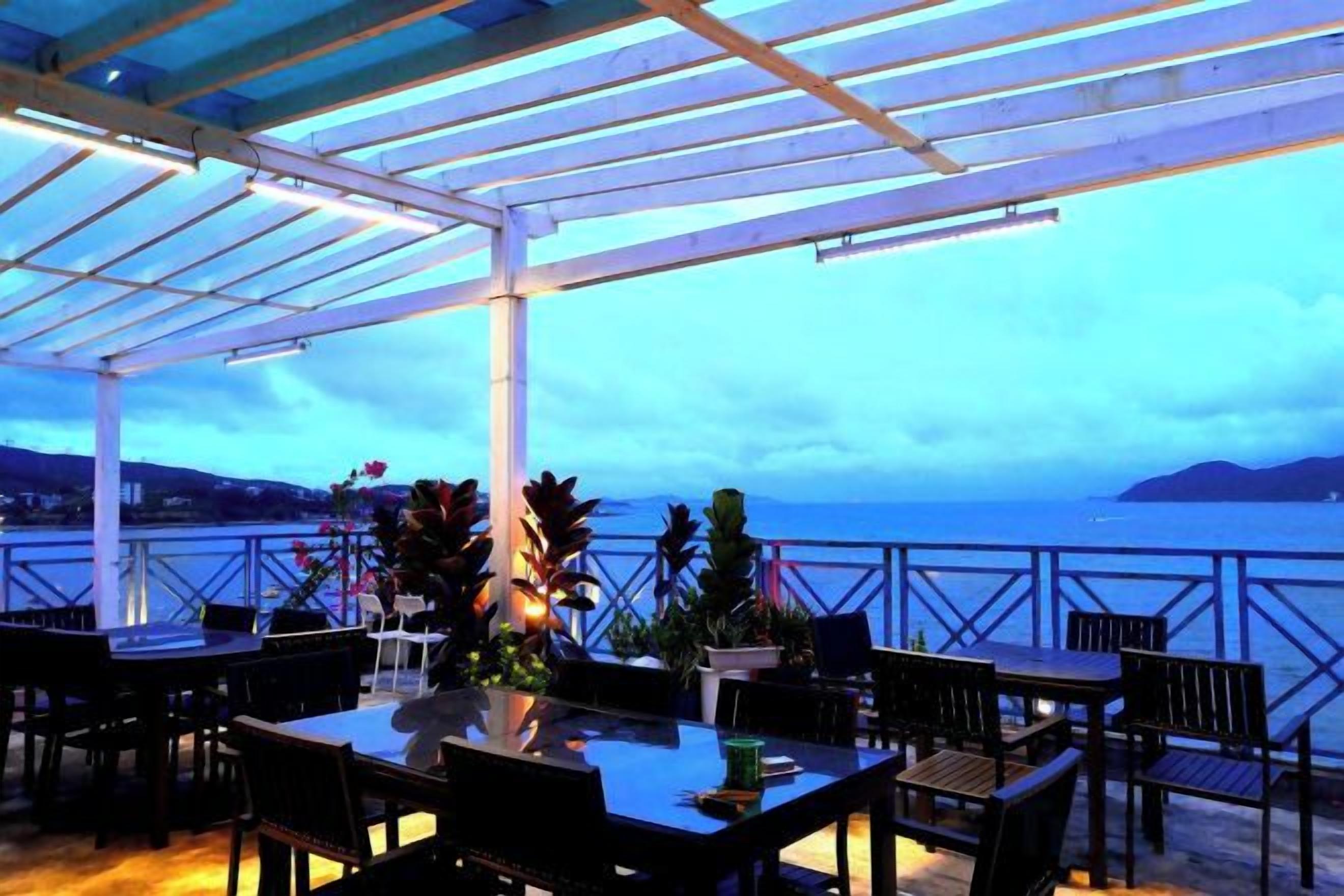 An outdoor patio with tables and chairs, overlooking a body of water.