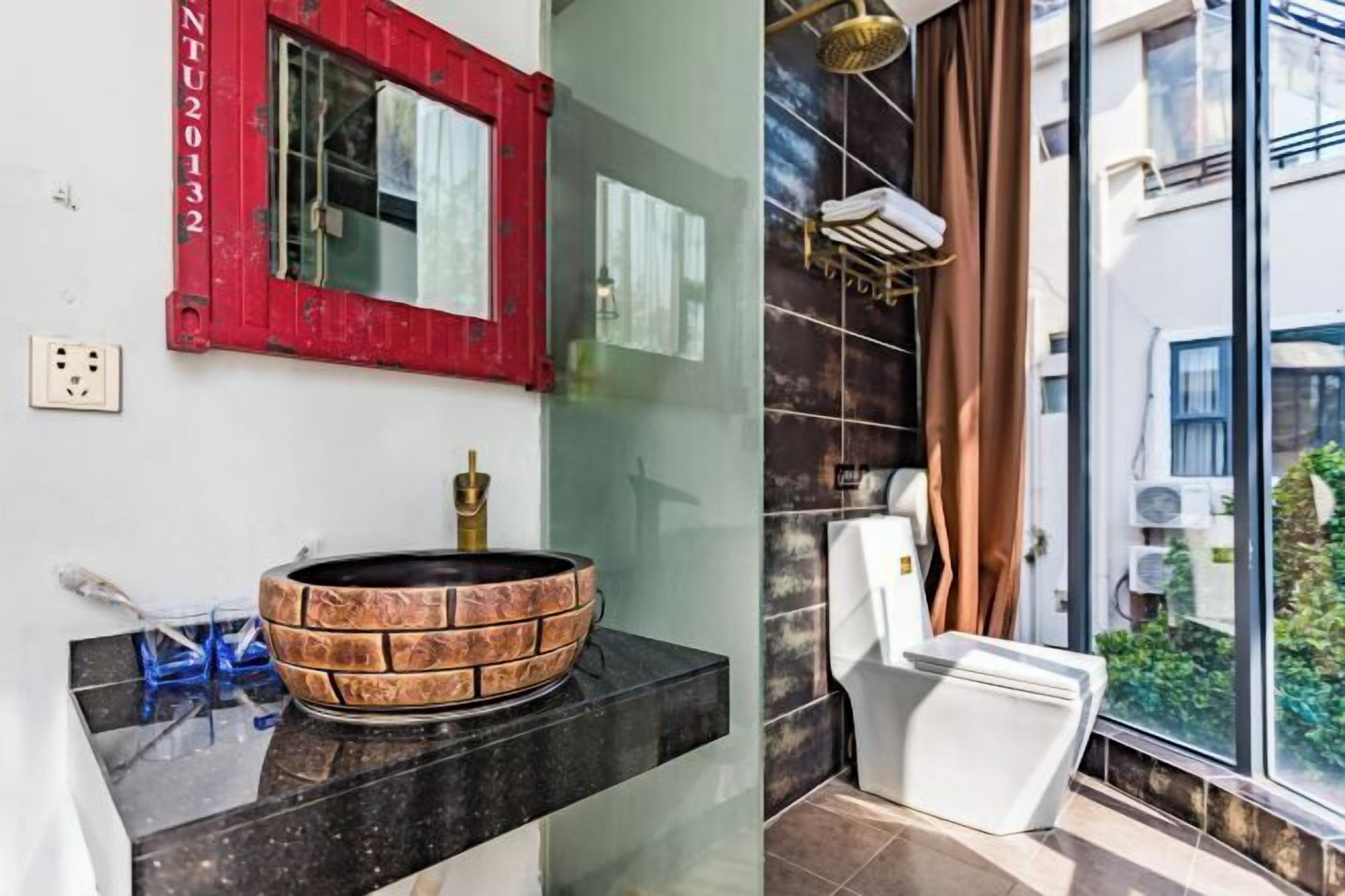 Un baño de diseño moderno, con un lavamanos de original patrón de ladrillo, un inodoro blanco y un amplio ventanal con vistas al exterior.