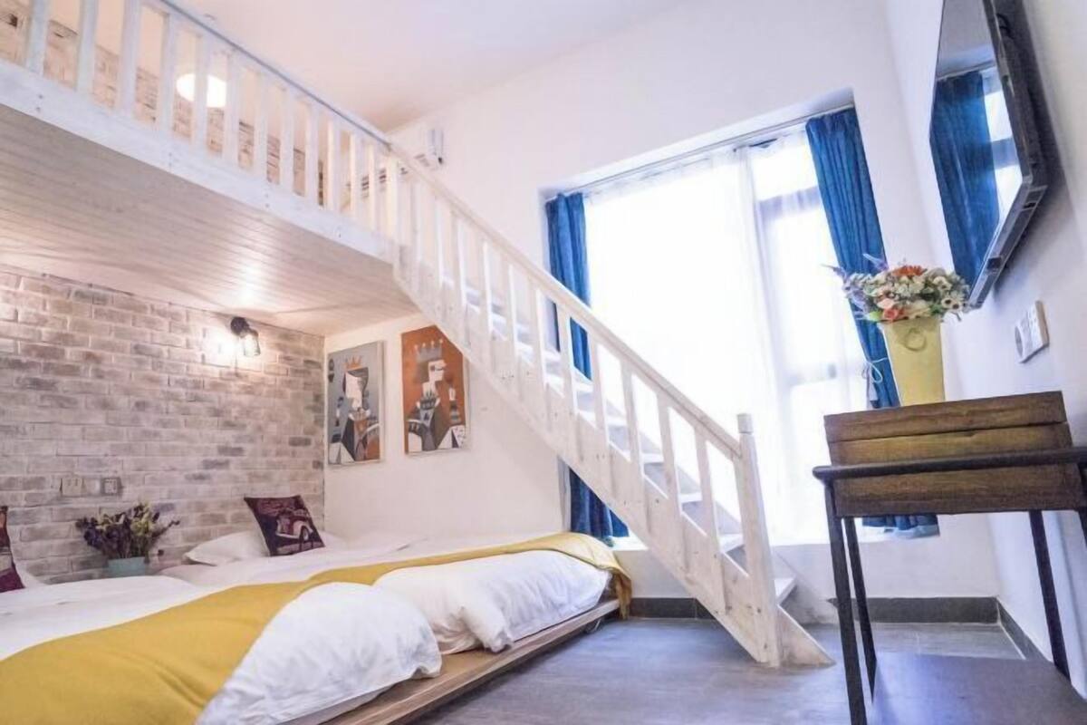 Un dormitorio con cama tipo altillo, una escalera y vistas al exterior.