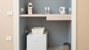 A small, enclosed storage space with a white refrigerator, a wicker basket, and a trash bin. - Art Room n3 (Meta)