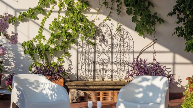 A patio with white chairs, a glass-top table, and a decorative metal gate. - Art Room n3 (Meta)