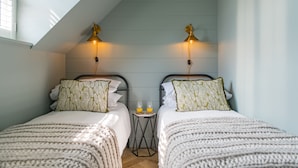 Een slaapkamer met twee bedden, een klein tafeltje met twee glazen jus d'orange en twee wandlampen.