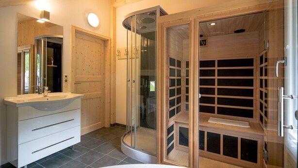 A modern bathroom with a curved shower enclosure, a vanity with drawers, and a large mirror. - Murau 5 - Chalet Murlaub (Murau)