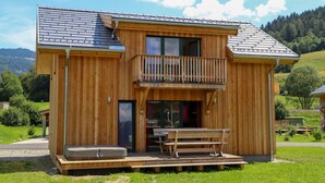 A wooden cabin with a balcony, a hot tub, and a picnic table. - Murau 5 - Chalet Murlaub (Murau)