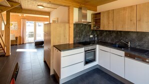 A modern kitchen with wooden cabinets, a black countertop, and a built-in oven. - Murau 13 - Chalet Murau (Murau)