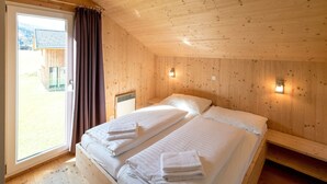 A wooden room with two beds, a window, and a view of a building outside. - Murau 13 - Chalet Murau (Murau)
