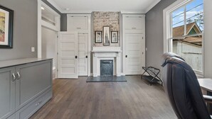 A spacious room with a fireplace, grey walls, and a large window. - Historic 4th and Gill Charmer (Mid-Term Available) (Knoxville)