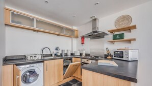 A compact kitchen with a built-in washer, dishwasher, and microwave. - Elegant Apartment in City Centre • Fast Wifi • Smart TV • Access to Communal Gym (Northampton)