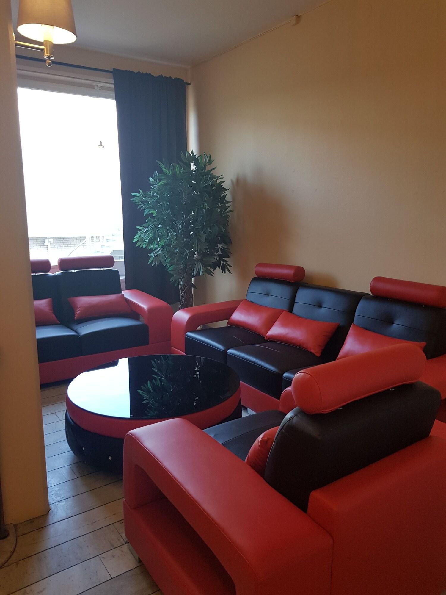 A modern living room with red and black sofas, a round coffee table, and a large potted plant.