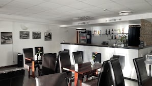 Un restaurante con zona de bar, sillas de cuero negro y un refrigerador lleno de bebidas.