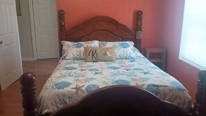 A bedroom with a wooden bed, floral bedding, and a 'Relax' pillow.