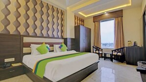 A hotel room with a bed, a desk, a chair, and a view of the city. - Charming 9-bedroom hotel with AC and WiFi in brilliant Agra (Agra)