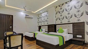 A hotel room with two beds, a wooden floor, a wall air conditioner, and a patterned wallpaper. - Charming 9-bedroom hotel with AC and WiFi in brilliant Agra (Agra)