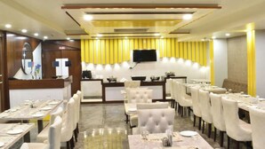 A dining area with tables set for service, a television mounted on the wall, and a reception desk. - Charming 9-bedroom hotel with AC and WiFi in brilliant Agra (Agra)